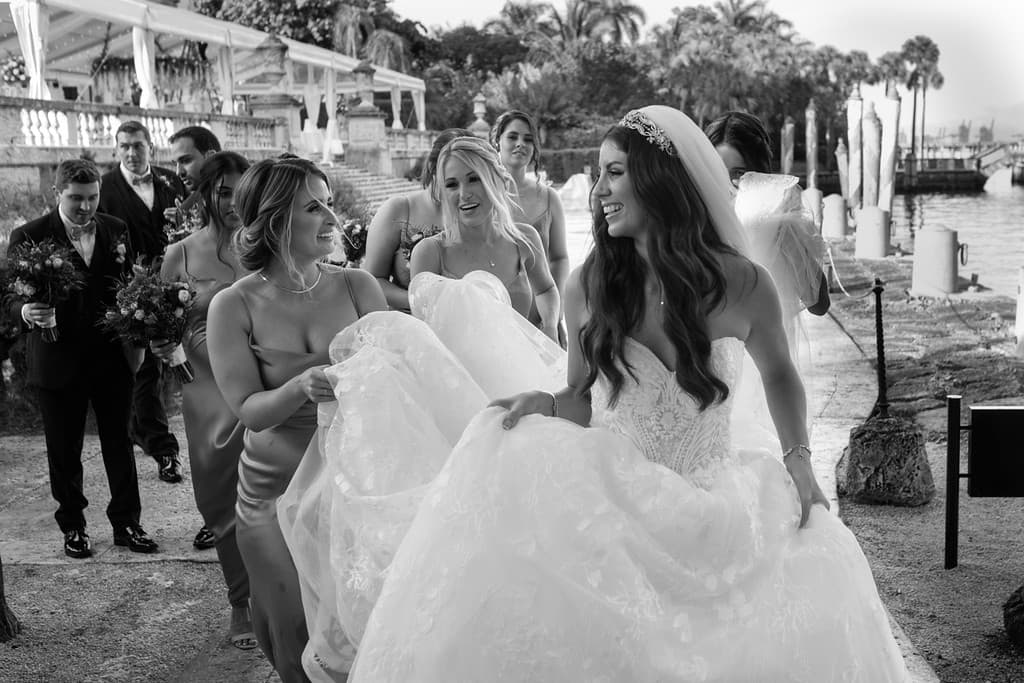 A black and white photograph of a bride walking away down an aisle as guests watch