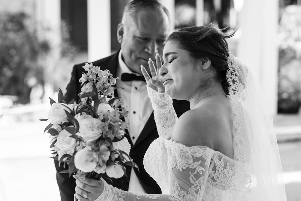 A black and white close-up of a bride and an older man, foreheads nearly touching