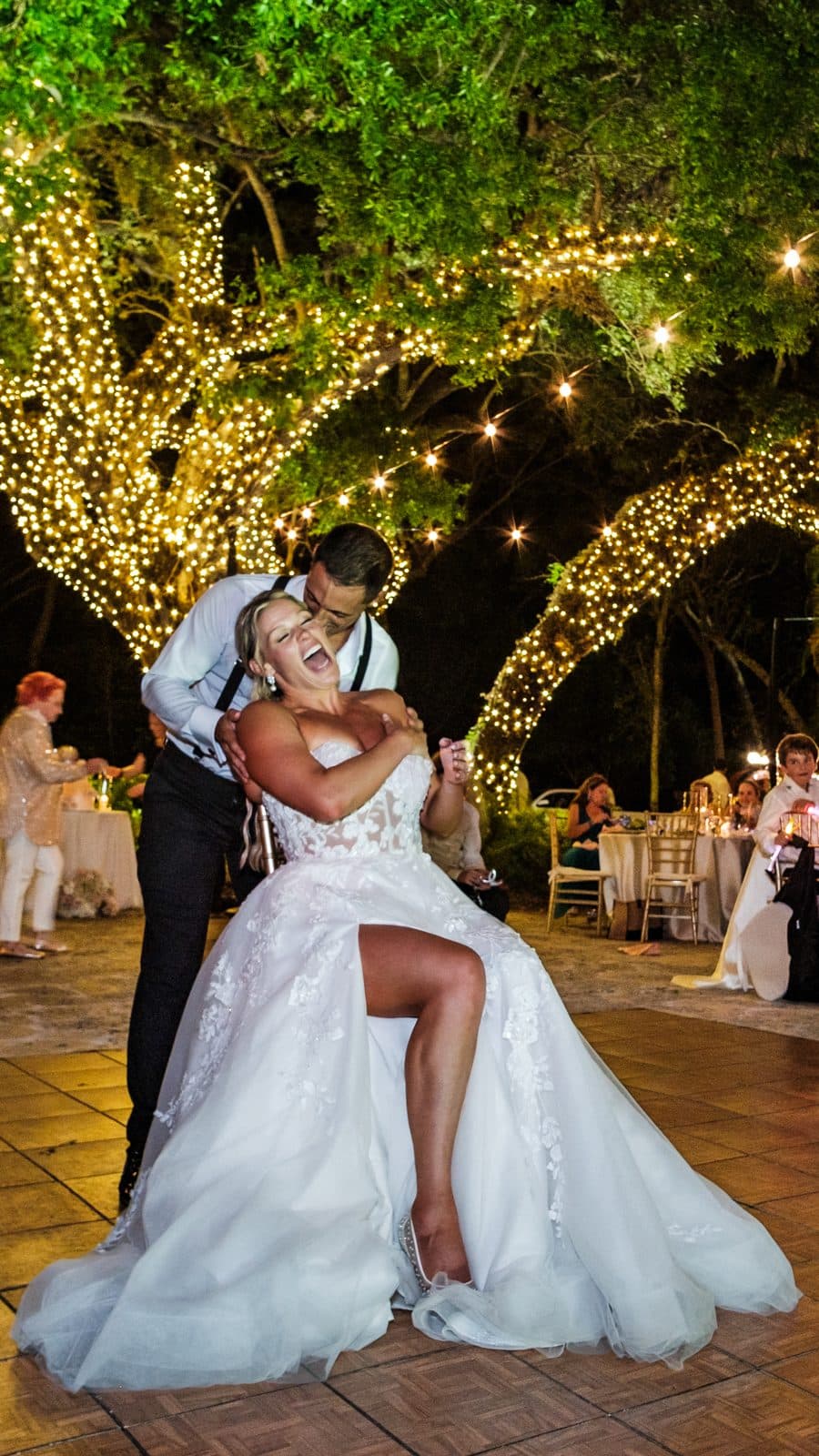 Alyssa and Chris dancing under trees wrapped in string lights at Deering Estates